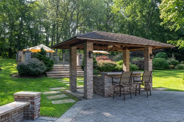 a backyard of a house with table and chairs under an umbrella