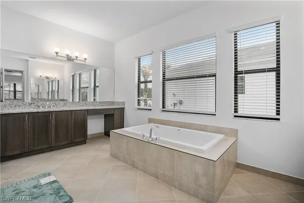 a spacious bathroom with a granite countertop sink and a bathtub