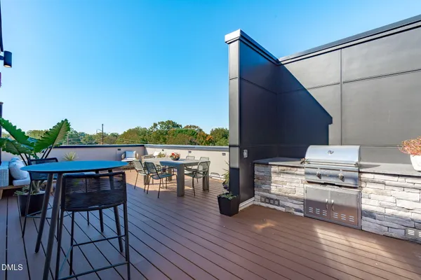 a view of a roof deck with table and chairs a barbeque with wooden floor and fence