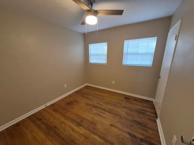 an empty room with a ceiling fan and wooden floor