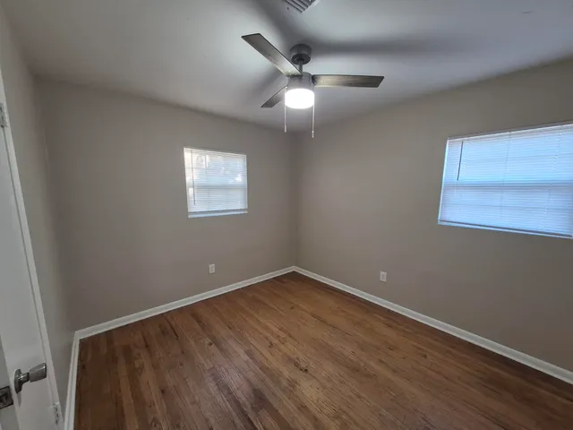 an empty room with wooden floor and windows