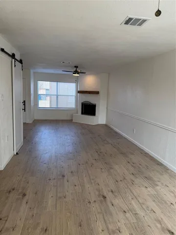 a view of empty room with wooden floor and fireplace