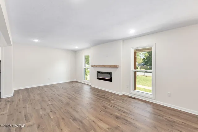 an empty room with windows and fireplace
