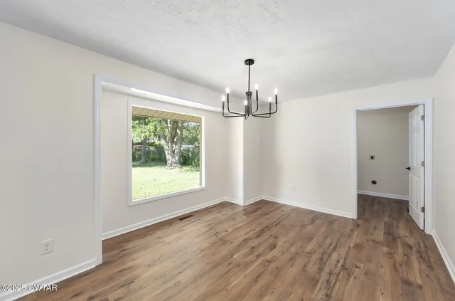 a view of empty room with wooden floor and window