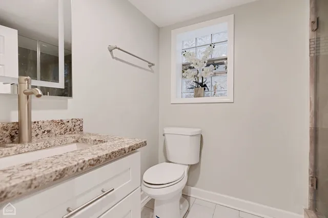 a bathroom with a granite countertop toilet a sink and a mirror
