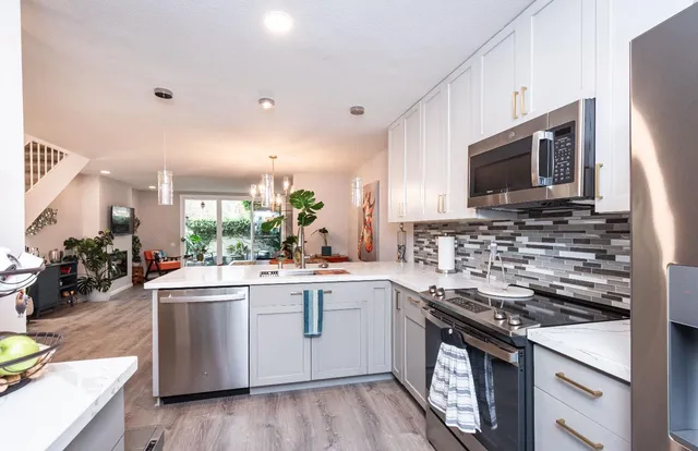 a dining hall with stainless steel appliances kitchen island granite countertop a table chairs and a refrigerator