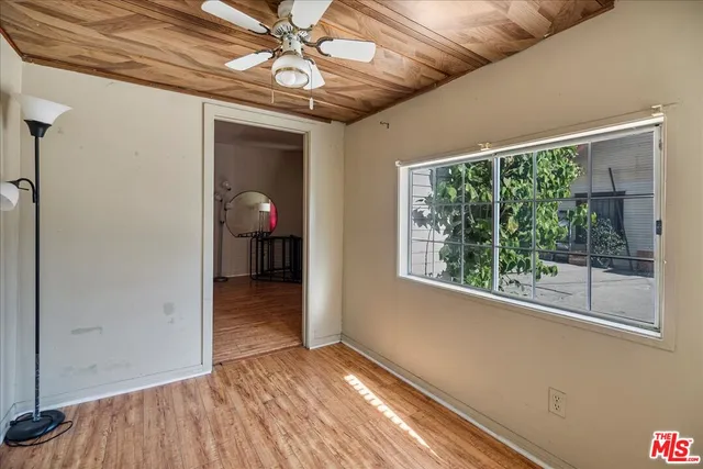 a view of empty room with wooden floor and fan