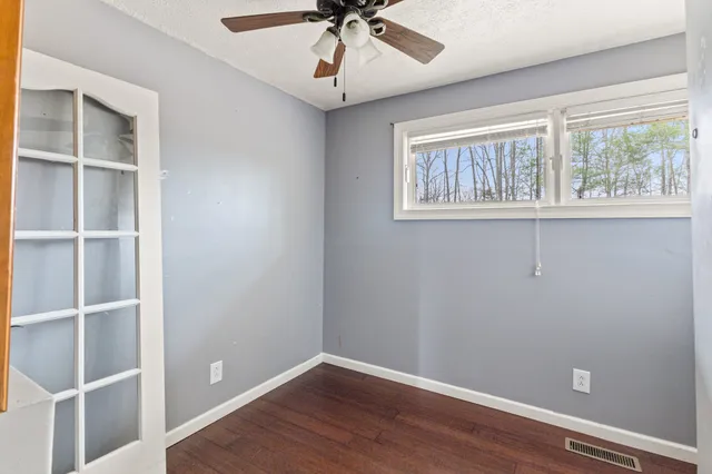 a view of an empty room with a window and wooden floor