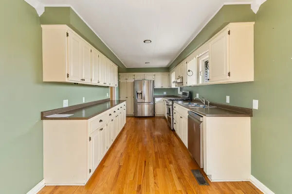 a kitchen with granite countertop a sink a counter top space stainless steel appliances and cabinets