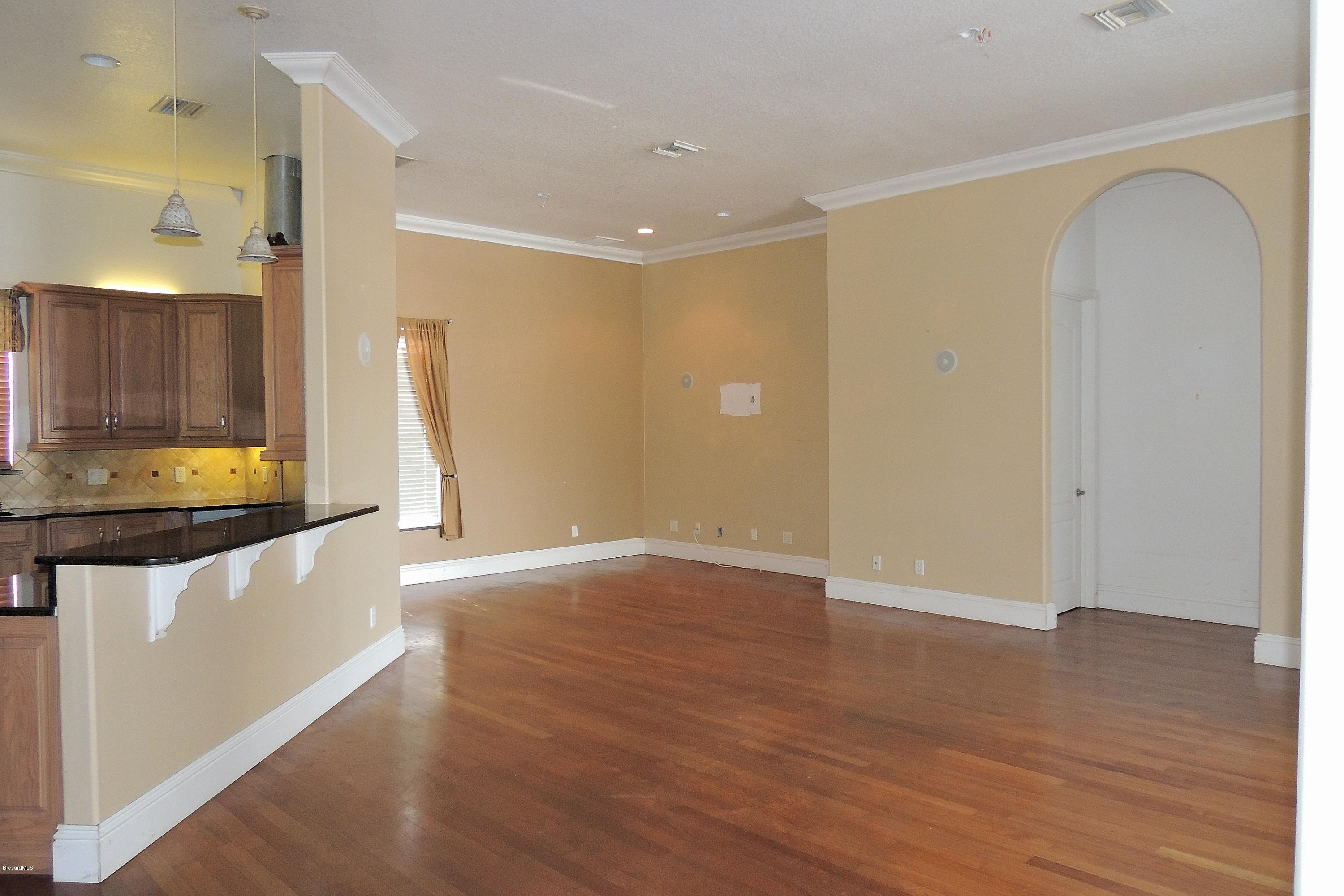 1120 Riviera Drive Northeast Palm Bay, FL 32905 - Photo 16 of 44 a view of an empty room with wooden floor and a window