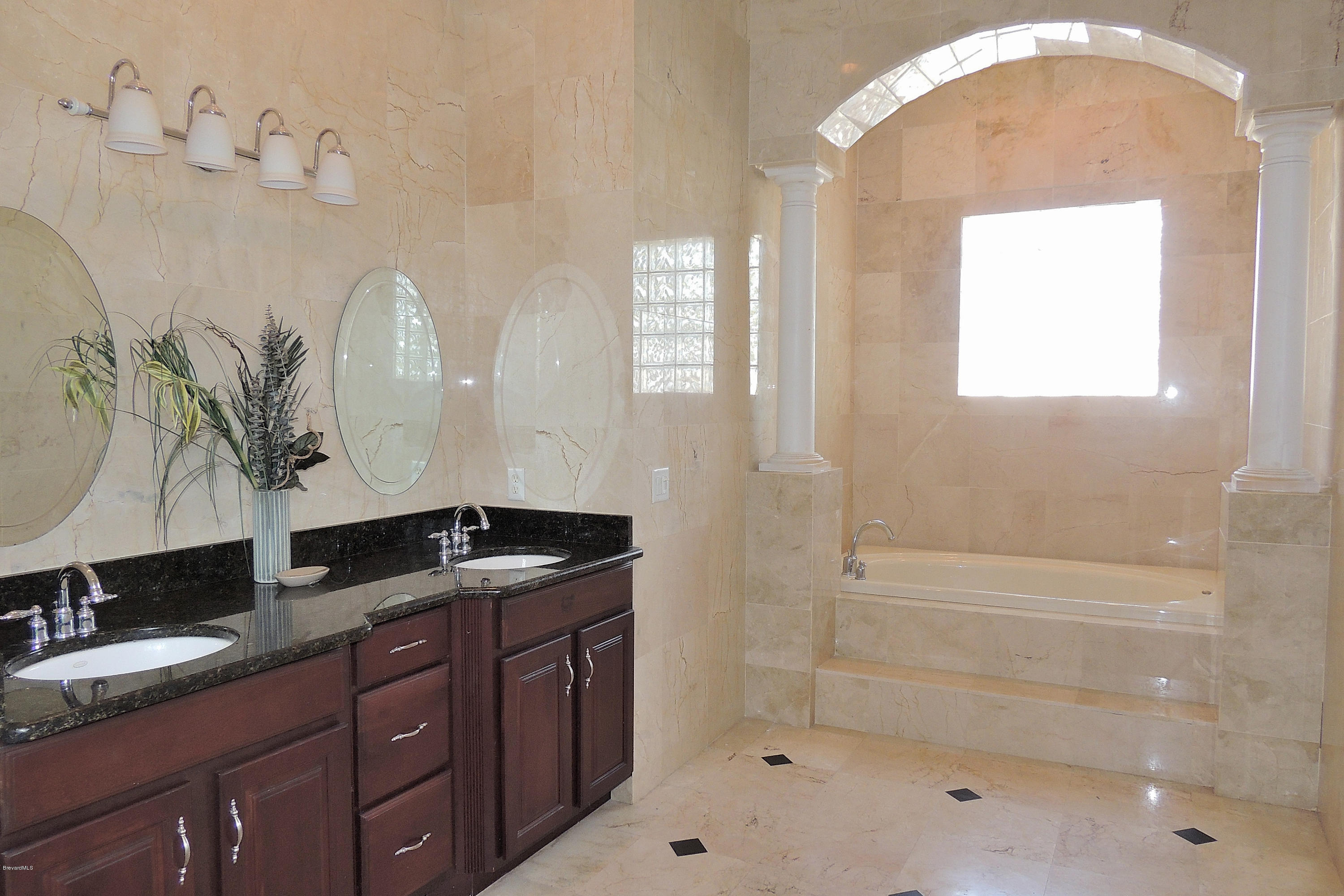 1120 Riviera Drive Northeast Palm Bay, FL 32905 - Photo 24 of 44 a bathroom with a granite countertop sink a mirror and shower