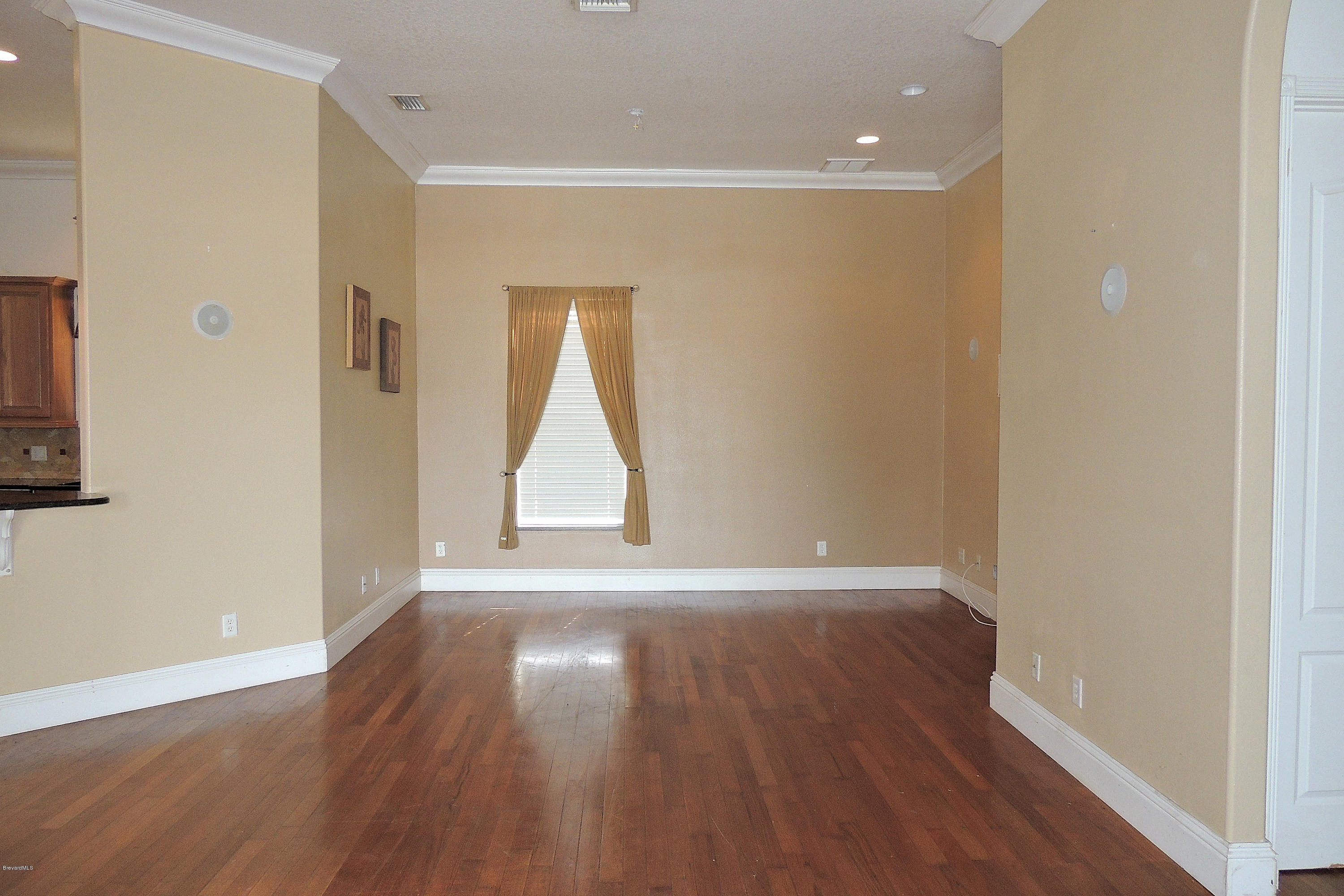 1120 Riviera Drive Northeast Palm Bay, FL 32905 - Photo 4 of 44 a view of an empty room with wooden floor and a window