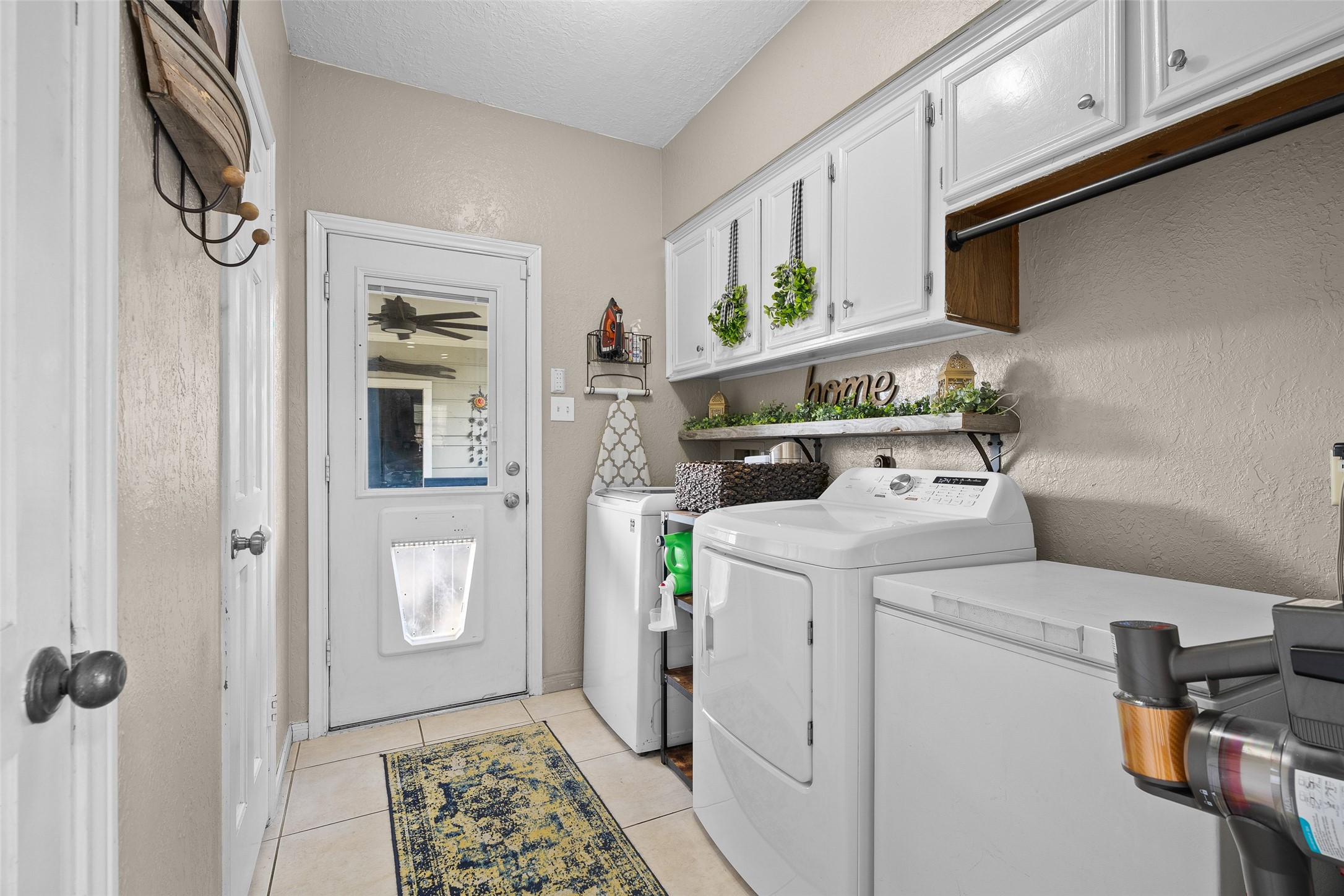 41 Windsor Drive Conroe, TX 77304 - Photo 32 of 39 Laundry room with tile flooring, built-in upper cabinets for storage, and space for full-size washer and dryer. Includes an exterior door providing direct backyard access.