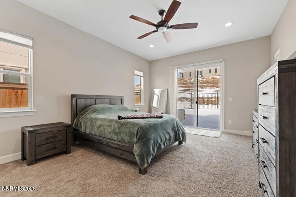 a spacious bedroom with a bed a dresser and a large window