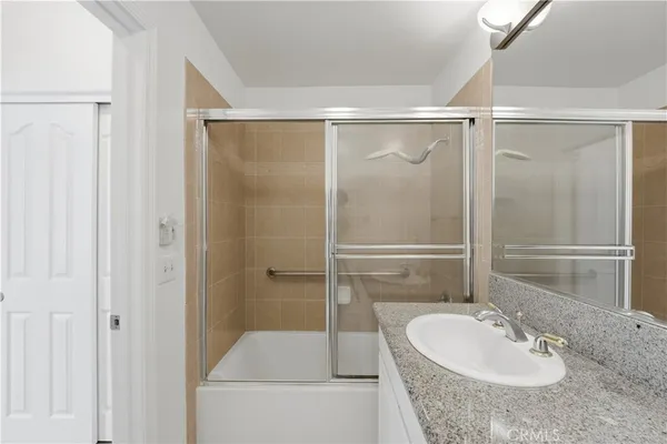 a bathroom with a granite countertop sink mirror and shower