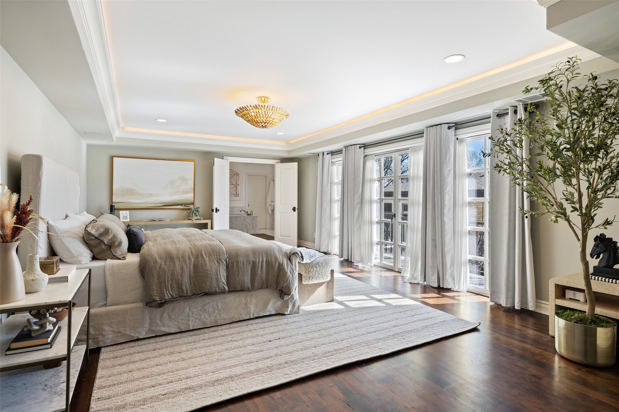 1810 West 35th Street Austin, TX 78703 - Photo 17 of 40 This primary suite is a tranquil retreat, where French doors flood the space with golden light, rich wood floors add warmth, and a statement chandelier.