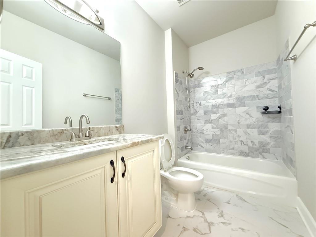 3500 Millwater Crossing Northeast Dacula, GA 30019 - Photo 34 of 72 a bathroom with a granite countertop sink a toilet a mirror a bathtub and shower