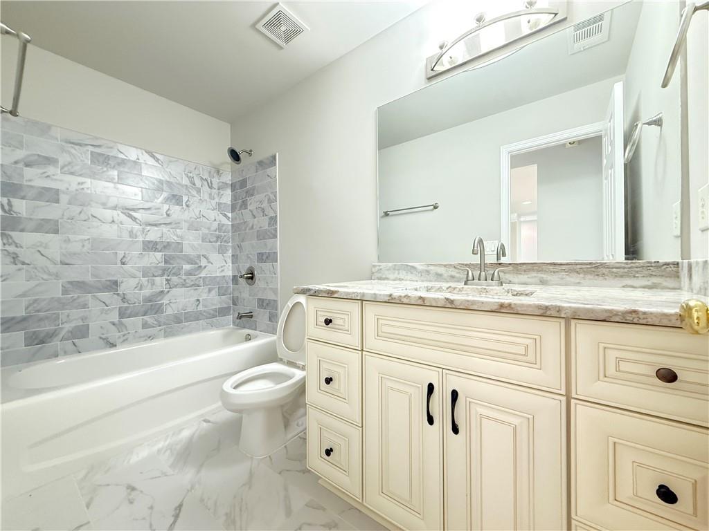 3500 Millwater Crossing Northeast Dacula, GA 30019 - Photo 46 of 72 a bathroom with a granite countertop toilet a sink and a bathtub