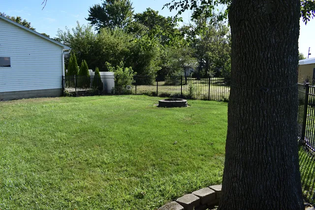 a view of a backyard with wooden fence and a bench