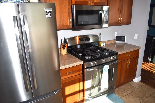 a kitchen with stainless steel appliances granite countertop a refrigerator a stove top oven and a sink