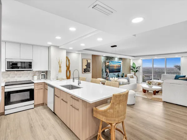 a kitchen with stainless steel appliances a sink a microwave a refrigerator and cabinets