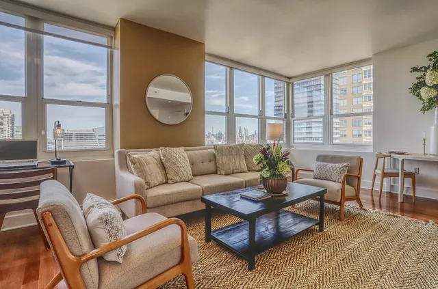 a living room with furniture a table and large windows