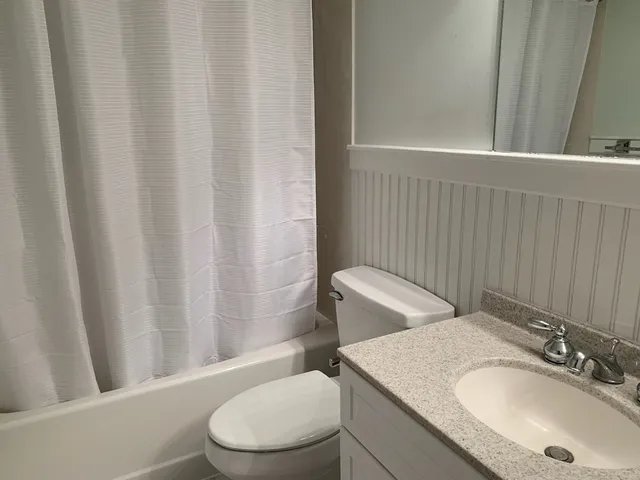 a bathroom with a granite countertop sink toilet and a mirror