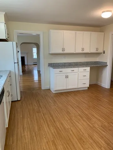 a kitchen with stainless steel appliances granite countertop a dishwasher a stove and white cabinets with wooden floor