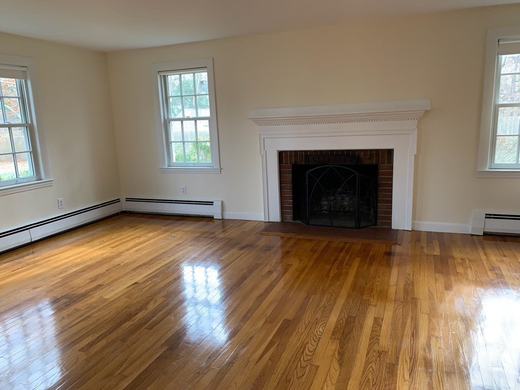 43 West Street Beverly, MA 01915 - Photo 4 of 15 an empty room with wooden floor fireplace and windows