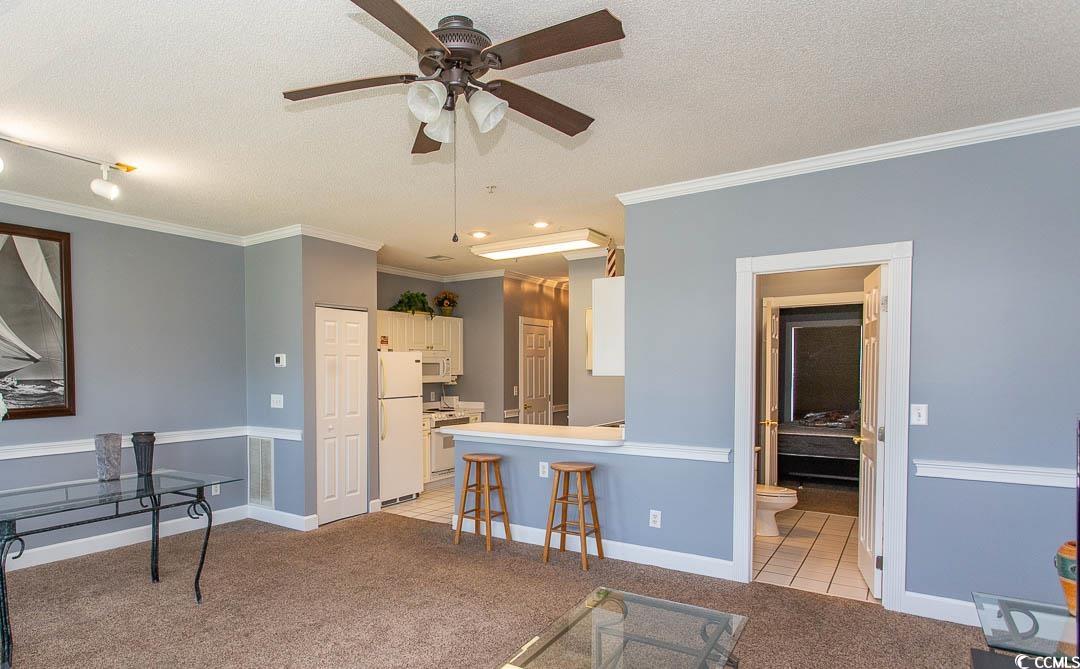 4823 Orchid Way, Unit 2203 Myrtle Beach, SC 29577 - Photo 15 of 36 Kitchen featuring a ceiling fan, white appliances, a textured ceiling, light colored carpet, and white cabinetry