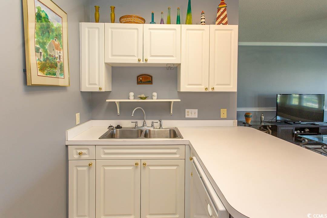 4823 Orchid Way, Unit 2203 Myrtle Beach, SC 29577 - Photo 7 of 36 Kitchen featuring light countertops, white cabinets, ornamental molding, and a sink