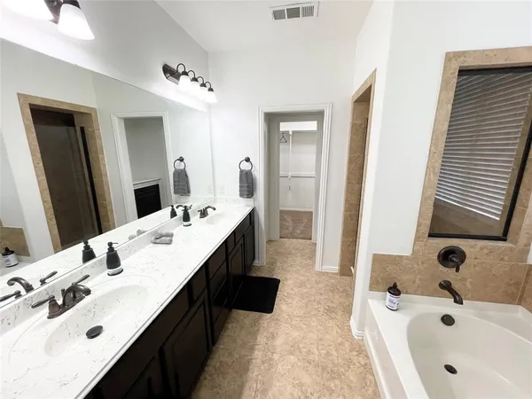 a spacious bathroom with a tub double sink and mirror