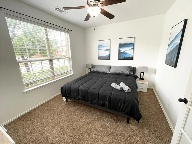 a spacious bedroom with a bed a dresser and a large window