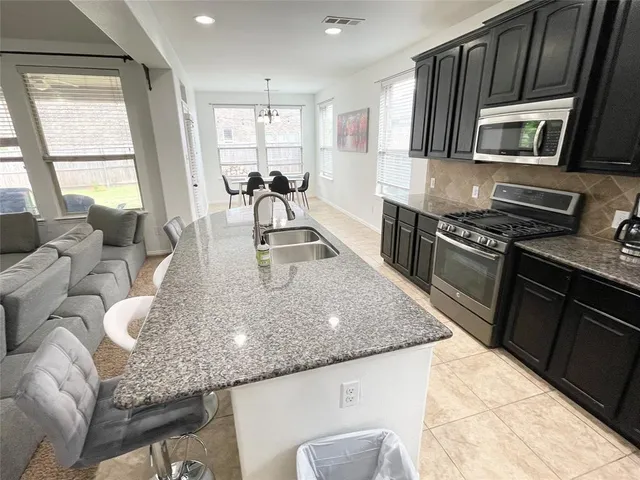 a kitchen with granite countertop kitchen island stainless steel appliances a sink stove and microwave