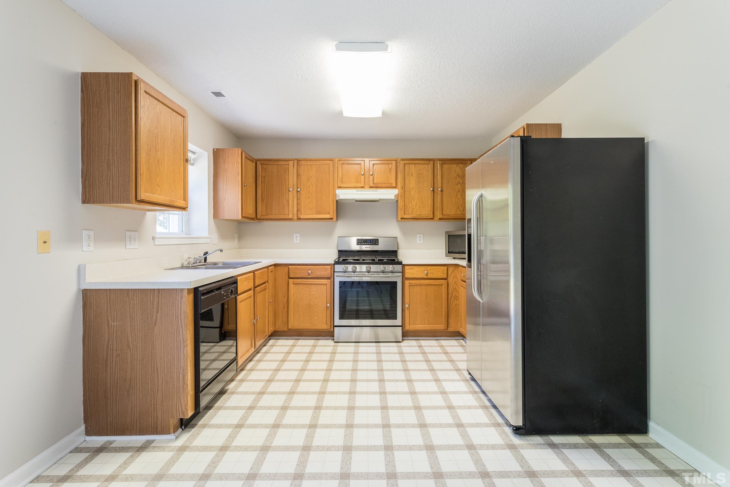 4411 Nightfall Court Durham, NC 27713 - Photo 12 of 28 a kitchen with a refrigerator a stove top oven and a sink