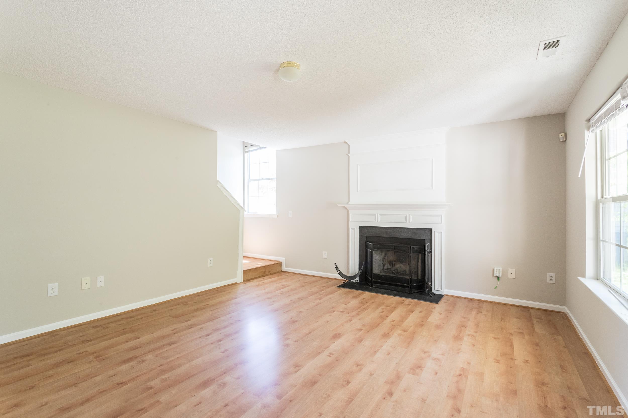 4411 Nightfall Court Durham, NC 27713 - Photo 6 of 28 an empty room with wooden floor fireplace and windows