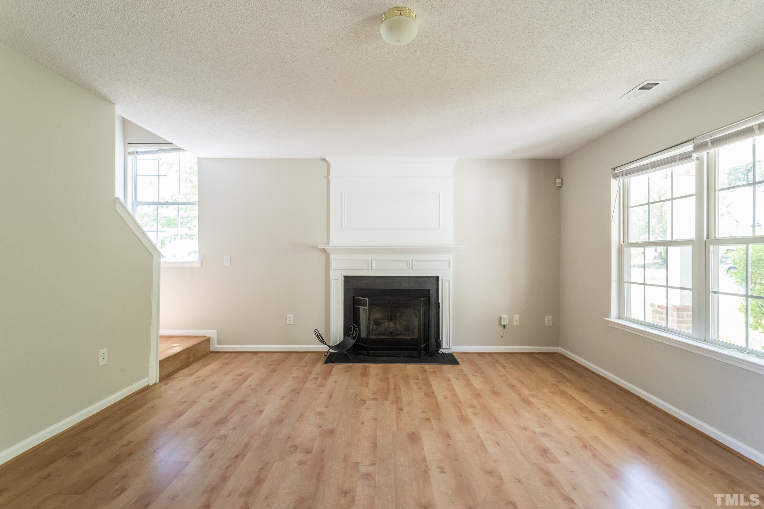 4411 Nightfall Court Durham, NC 27713 - Photo 7 of 28 an empty room with wooden floor fireplace and windows