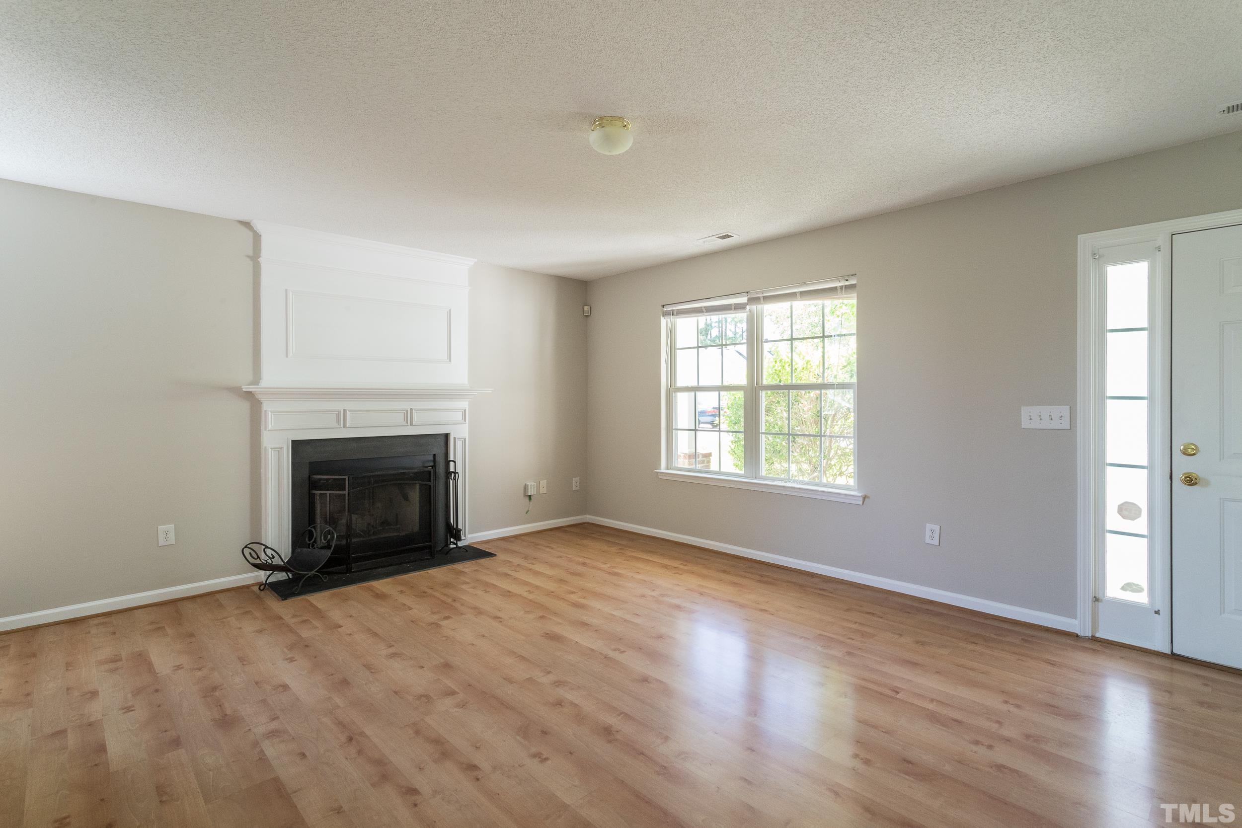 4411 Nightfall Court Durham, NC 27713 - Photo 8 of 28 an empty room with windows a fireplace and wooden floor