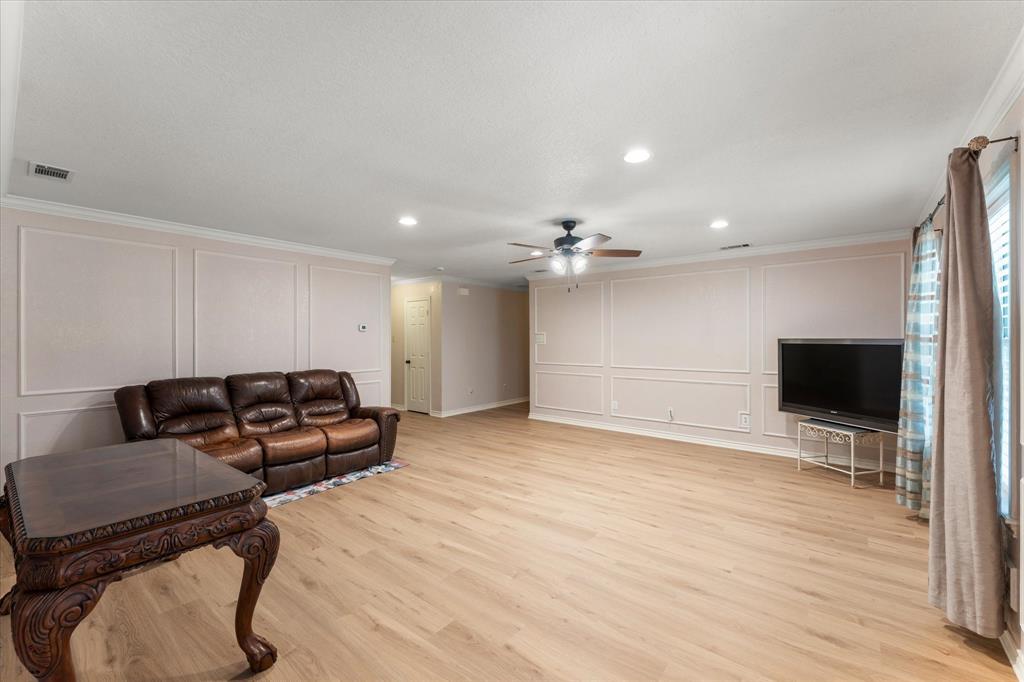 116 Meadowood Road Enchanted Oaks, TX 75156 - Photo 18 of 37 Spacious living area featuring light wood-finish flooring, decorative wall paneling, and a contemporary ceiling fan