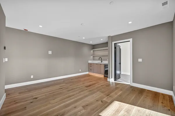 a view of an empty room with wooden floor and a fireplace