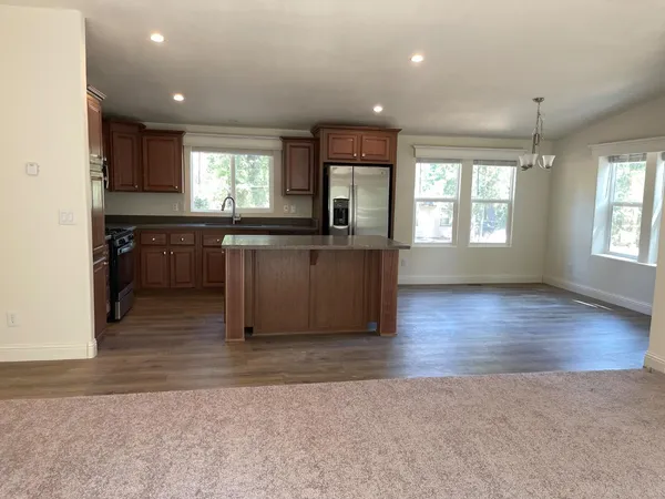 an open kitchen with kitchen island granite countertop a stove top oven a sink a counter space and cabinets