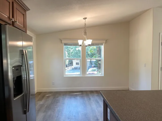 a view of a kitchen with a fridge wooden floor and a window