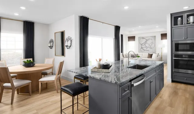 a kitchen with stainless steel appliances kitchen island granite countertop a refrigerator a stove and a dining table with wooden floor