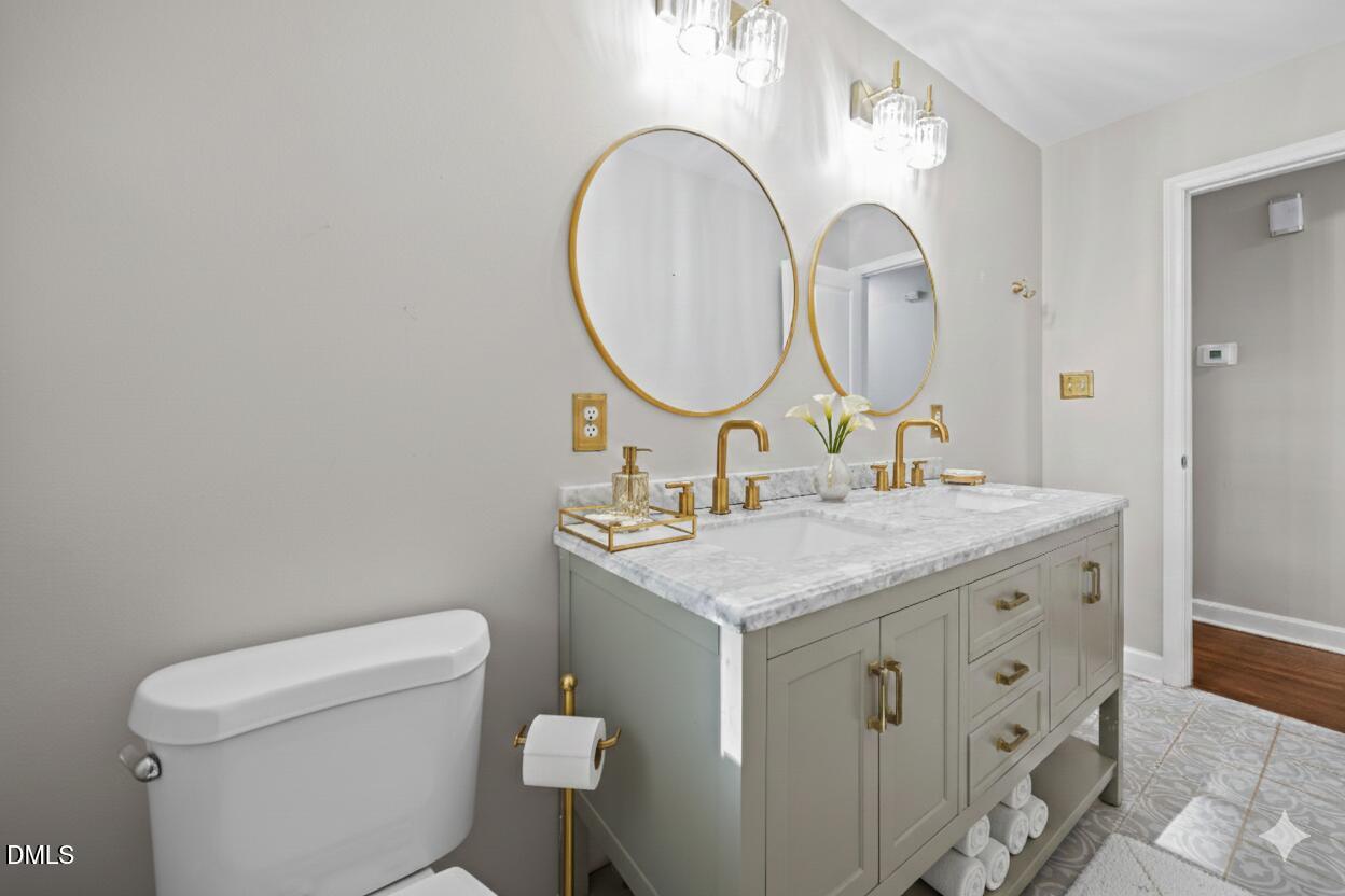 2950 Glenridge Drive Raleigh, NC 27604 - Photo 28 of 53 a bathroom with a granite countertop toilet a sink and a mirror