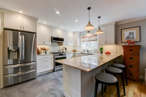 a kitchen with granite countertop a refrigerator a stove a sink a dining table and chairs