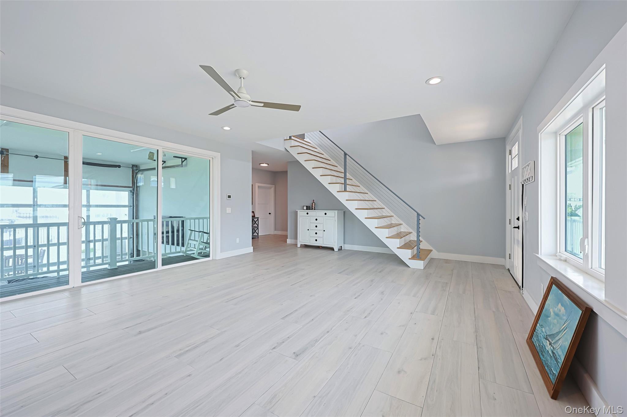 390 East Shore Road Lindenhurst, NY 11757 - Photo 14 of 27 an empty room with wooden floor windows and a ceiling fan