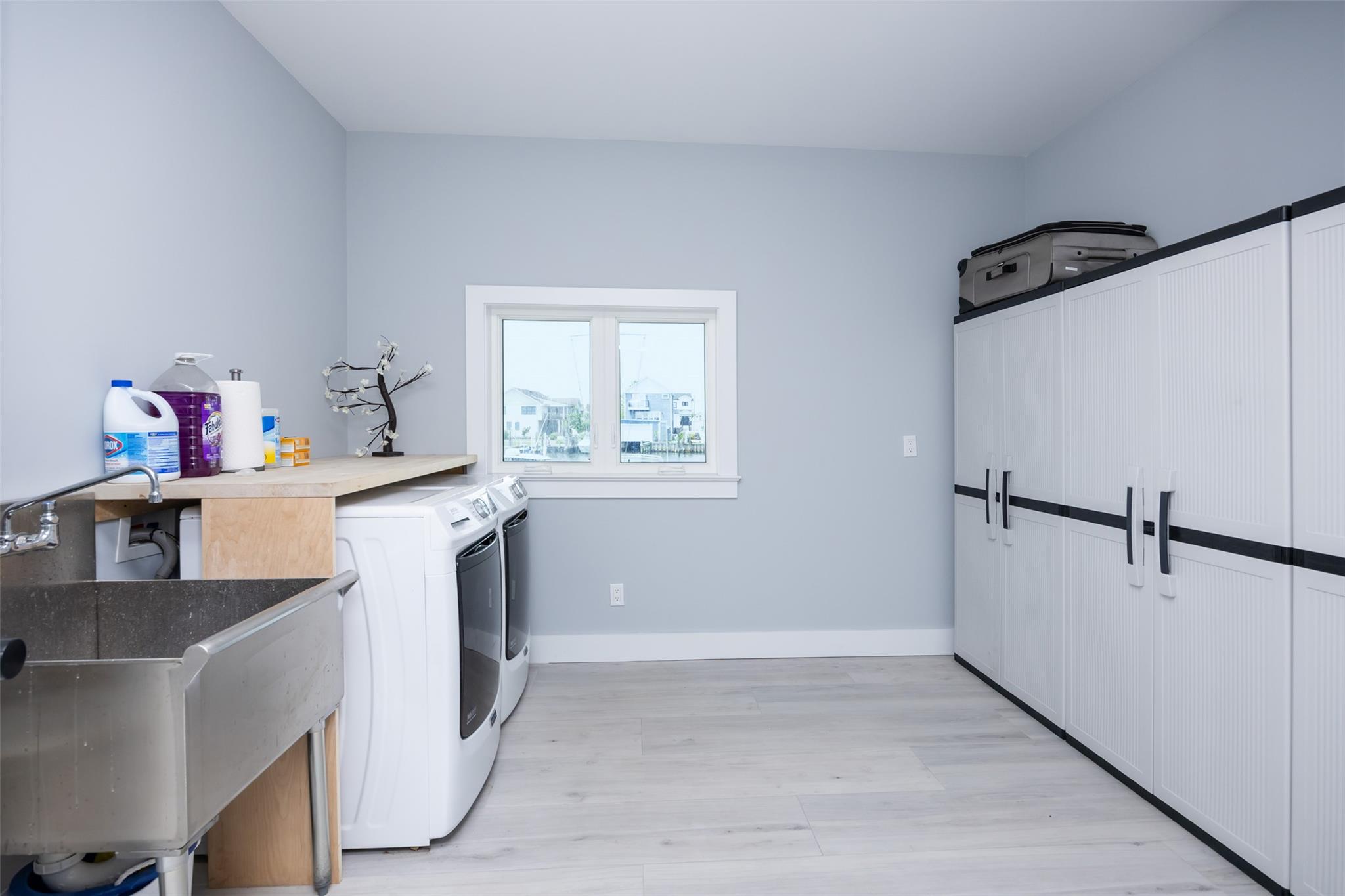 390 East Shore Road Lindenhurst, NY 11757 - Photo 26 of 27 Laundry room with independent washer and dryer, light wood-style flooring, and cabinet space
