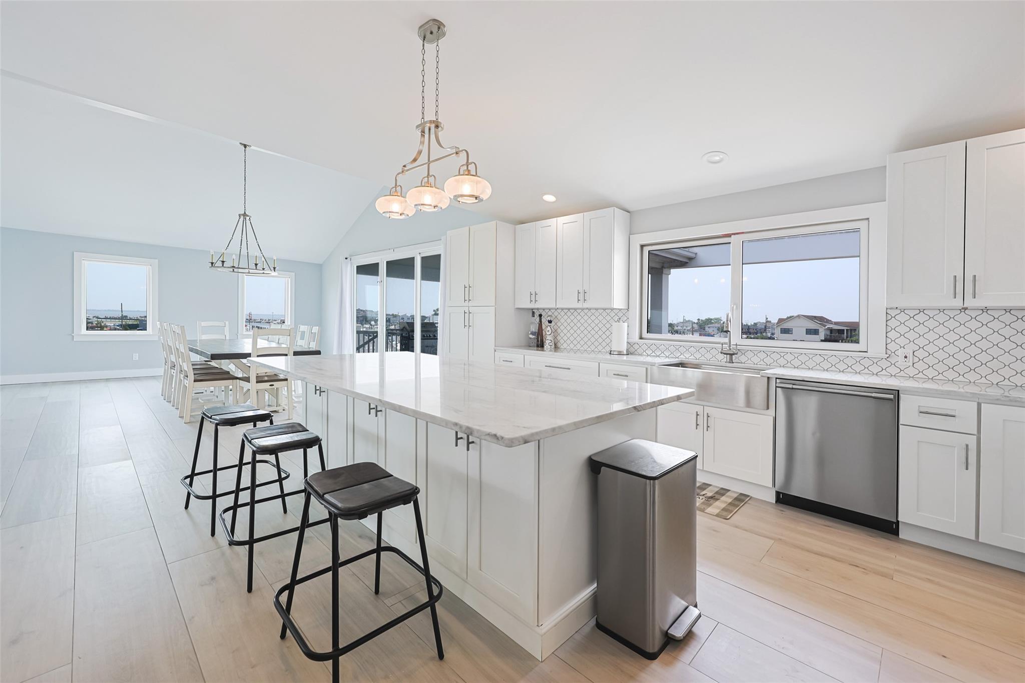390 East Shore Road Lindenhurst, NY 11757 - Photo 8 of 27 Kitchen with dishwasher, a kitchen bar, healthy amount of natural light, vaulted ceiling, and recessed lighting