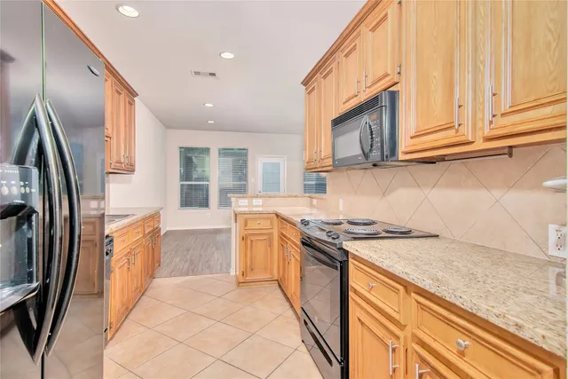 a kitchen with stainless steel appliances granite countertop a refrigerator a stove and a sink