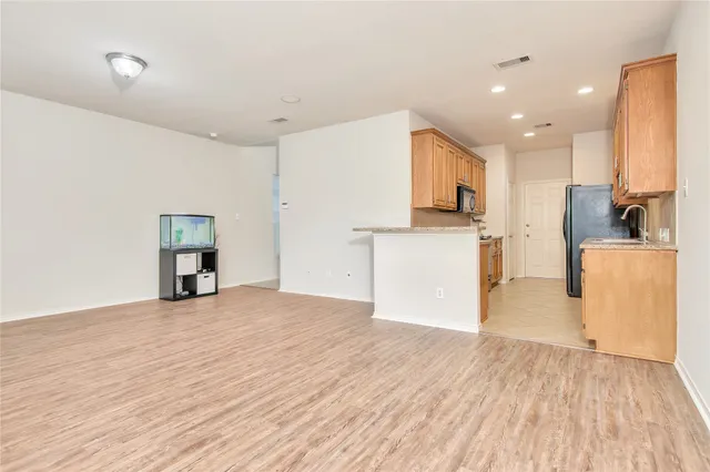 a view of a kitchen with a refrigerator a stove top oven and cabinets